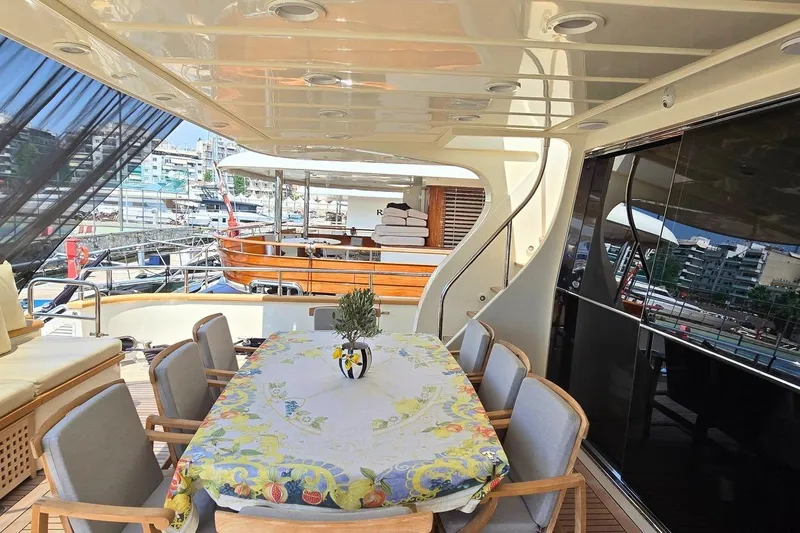 M/y Balkan Yacht Photos Pics Luxurious Falcon 102 yacht deck with dining area, 2007 model, featuring elegant seating and marina view.
