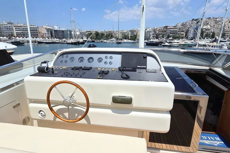 M/y Balkan Yacht Photos Pics Helm of 2007 Falcon 102 yacht with wooden steering wheel, docked in a marina.