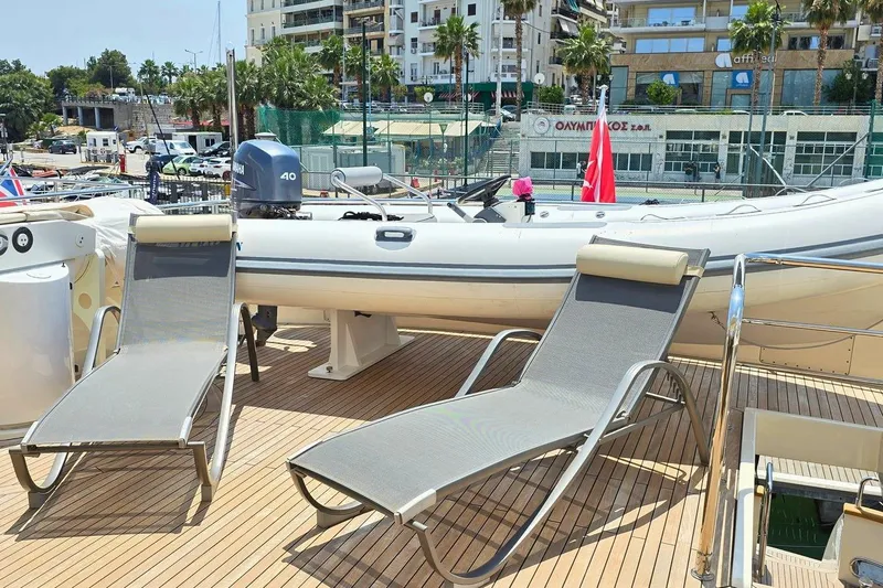 M/y Balkan Yacht Photos Pics Sun loungers on Falcon 102 yacht deck, 2007 model, with inflatable boat and cityscape background.