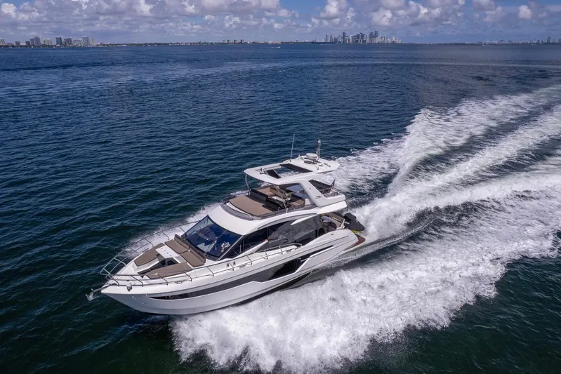 Mangogo Yacht Photos Pics 2021 Galeon 500 Fly yacht cruising on open water with city skyline in background.