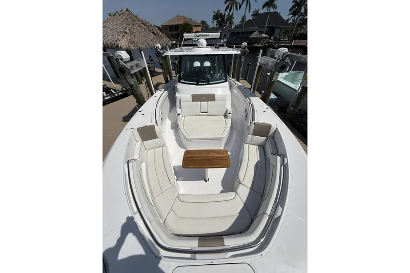  Yacht Photos Pics 2024 Bertram 39 CC boat with spacious seating and wooden table, docked near palm trees.