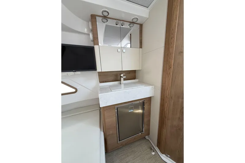  Yacht Photos Pics 2024 Bertram 39 CC bathroom with modern sink, mirror, and wood accents.