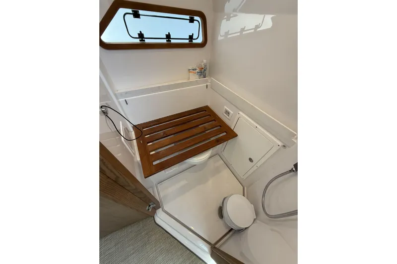  Yacht Photos Pics 2024 Bertram 39 CC boat bathroom with wooden seat and modern fixtures.