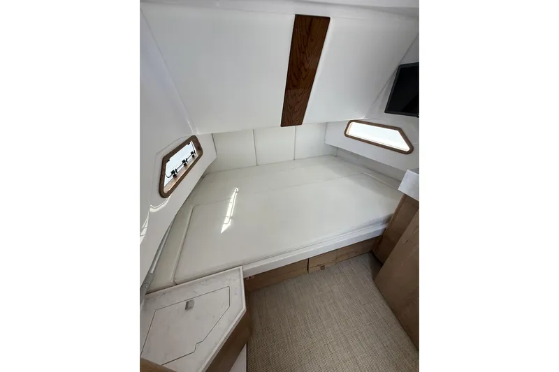  Yacht Photos Pics 2024 Bertram 39 CC cabin interior with bed, wooden accents, and windows.