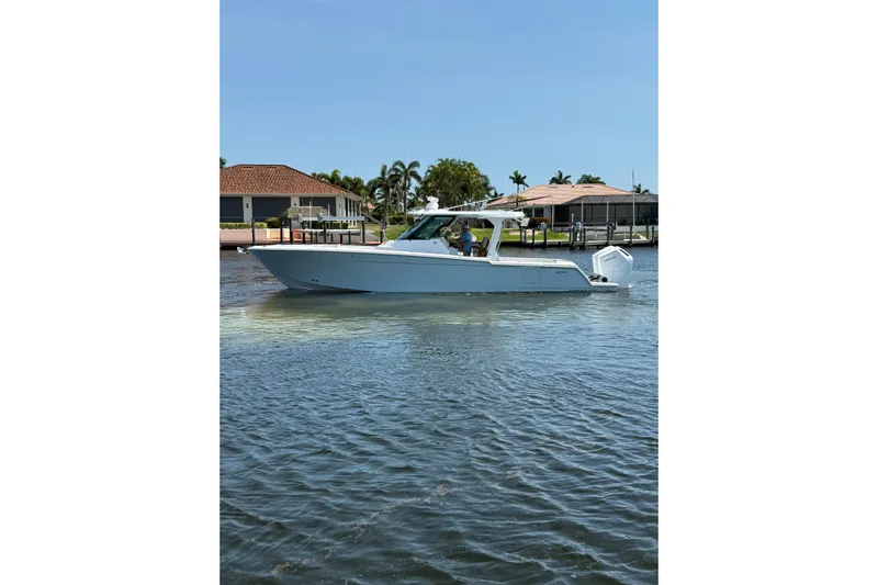  Yacht Photos Pics 2024 Bertram 39 CC boat cruising on a sunny day near waterfront homes.