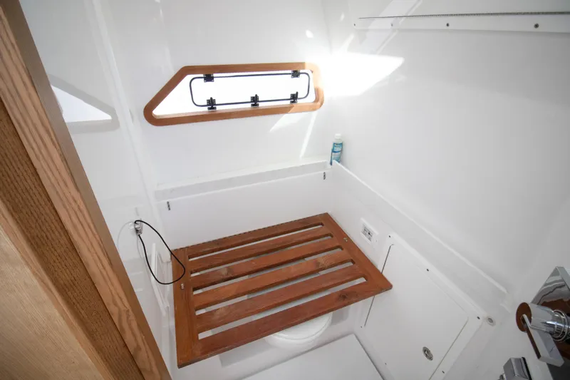  Yacht Photos Pics 2024 Bertram 39 CC boat bathroom with wooden seat and window.