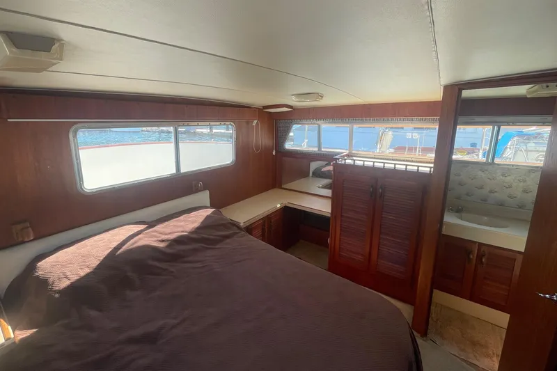  Yacht Photos Pics 1981 Tollycraft 48 Motor Yacht bedroom with wooden interior and large windows.