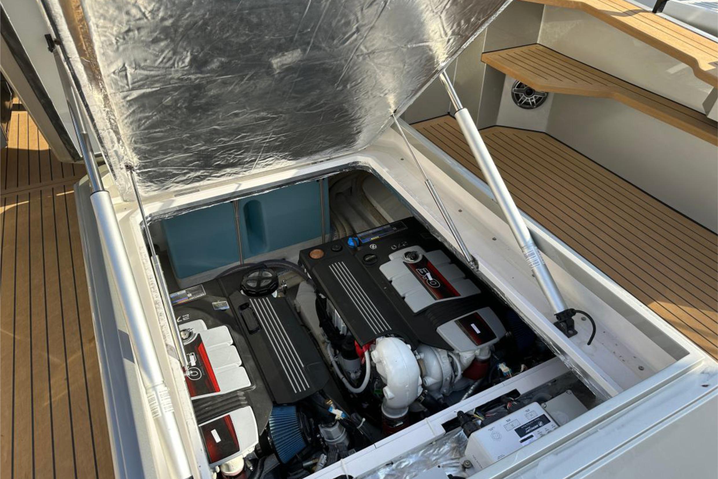 Open engine compartment of 2025 Focus 3X boat, showcasing dual engines and wooden deck.