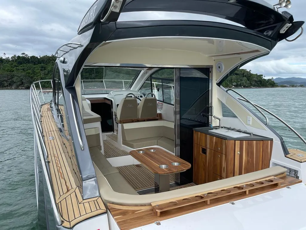 2022 Evolve 400HT yacht interior with seating, table, and kitchenette on the water.