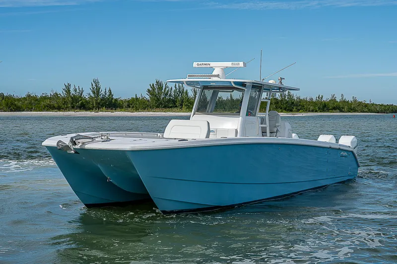  Yacht Photos Pics 2020 Invincible 37 Catamaran on water, blue hull, clear sky, coastal background.