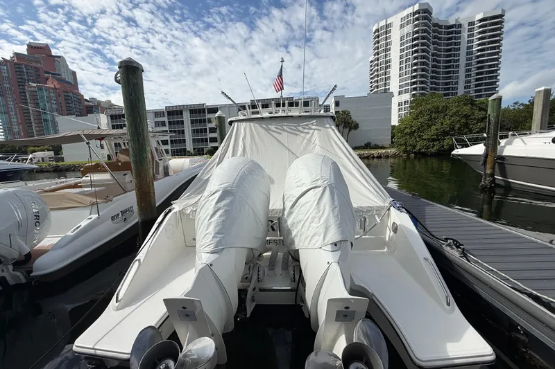 Alroma Yacht Photos Pics 2022 Pursuit S 358 Sport boat docked with covered engines, urban skyline background.