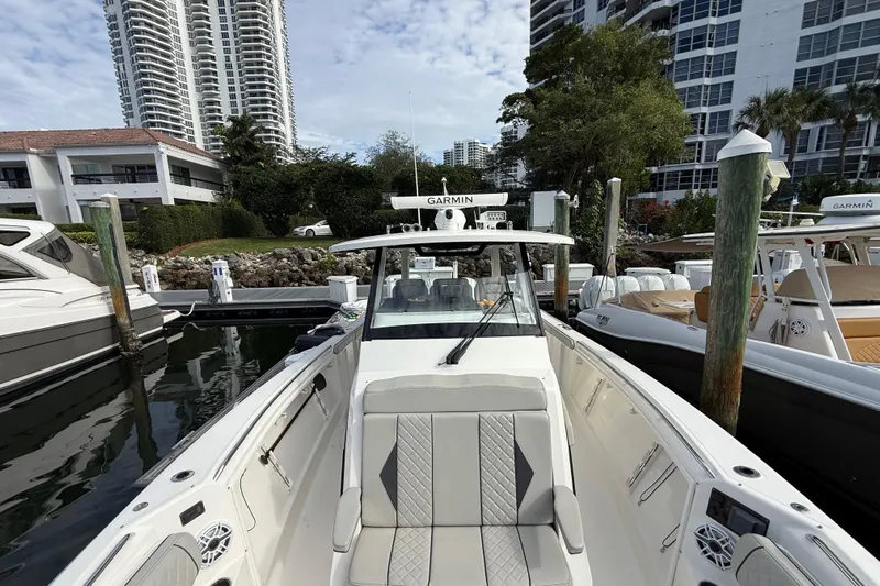 Alroma Yacht Photos Pics 2022 Pursuit S 358 Sport boat docked near modern buildings and lush greenery.