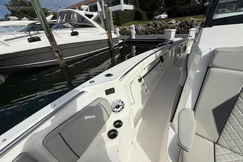 Alroma Yacht Photos Pics 2022 Pursuit S 358 Sport boat interior with seating and speaker, docked beside another boat.