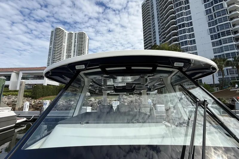 Alroma Yacht Photos Pics 2022 Pursuit S 358 Sport boat docked near high-rise buildings under a cloudy sky.