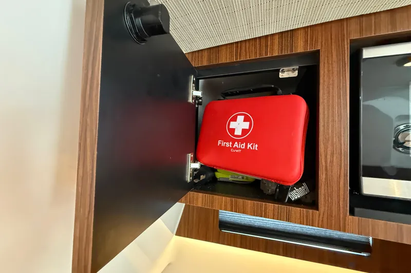 Alroma Yacht Photos Pics Red first aid kit in a wooden cabinet on a 2022 Pursuit S 358 Sport boat.