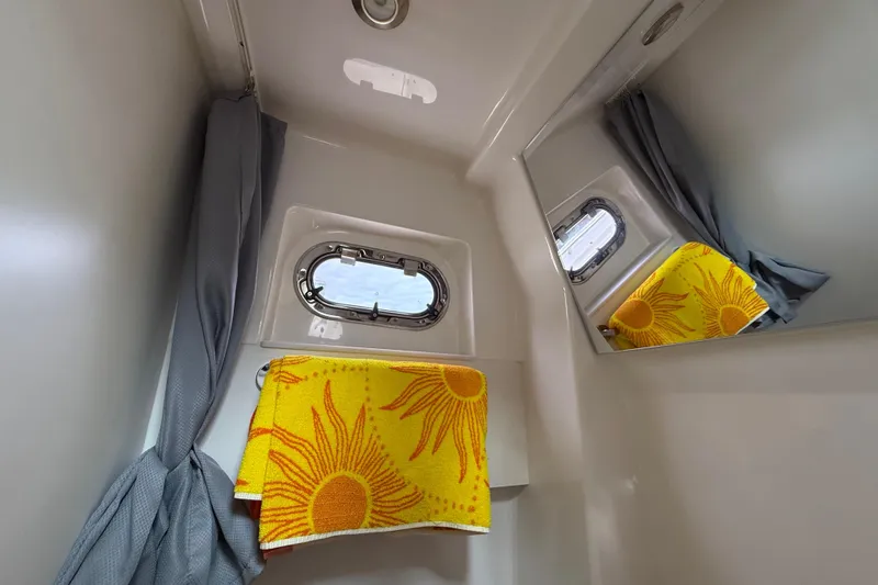 Alroma Yacht Photos Pics Compact bathroom in 2022 Pursuit S 358 Sport boat with porthole and sun-patterned towel.