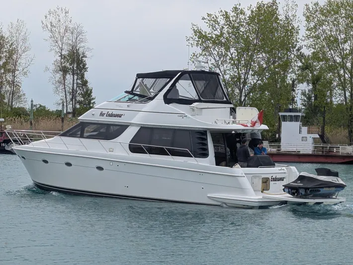 Her Endeavour II Yacht Photos Pics 1999 Carver 530 Voyager Pilothouse yacht cruising on a calm lake with trees in the background.