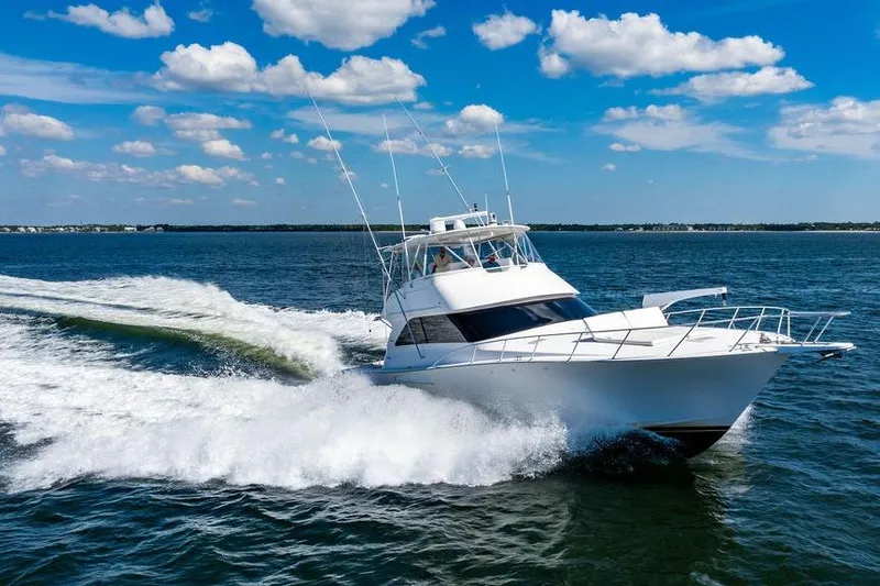 Reel Southern Yacht Photos Pics 2006 Viking 56 Convertible yacht cruising on open water under a clear blue sky.