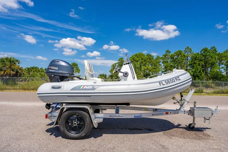 Reel Southern Yacht Photos Pics A small inflatable boat with Yamaha motor on a trailer under a clear blue sky.