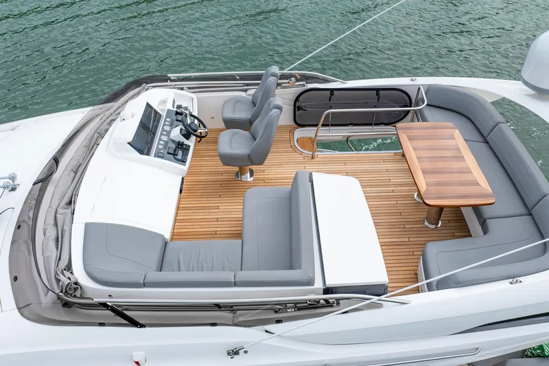 Cinderella Yacht Photos Pics 2017 Princess S65 yacht deck with seating, table, and helm, on calm water.