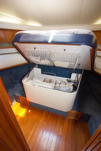 Sparrow Yacht Photos Pics 1995 Tiara Yachts 4000 Express cabin with raised bed storage, wooden flooring, and blue accents.