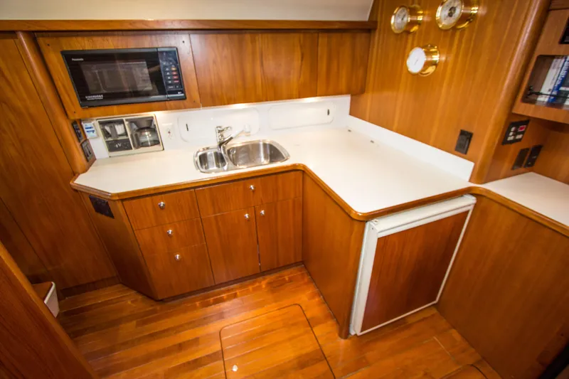 Sparrow Yacht Photos Pics 1995 Tiara Yachts 4000 Express galley with wood cabinetry, sink, microwave, and compact fridge.