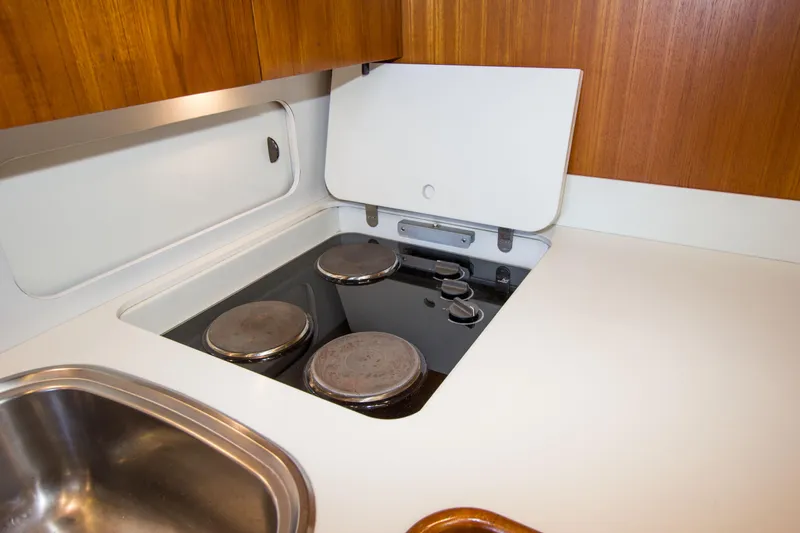 Sparrow Yacht Photos Pics 1995 Tiara Yachts 4000 Express kitchen with stove and sink, featuring wooden cabinetry.