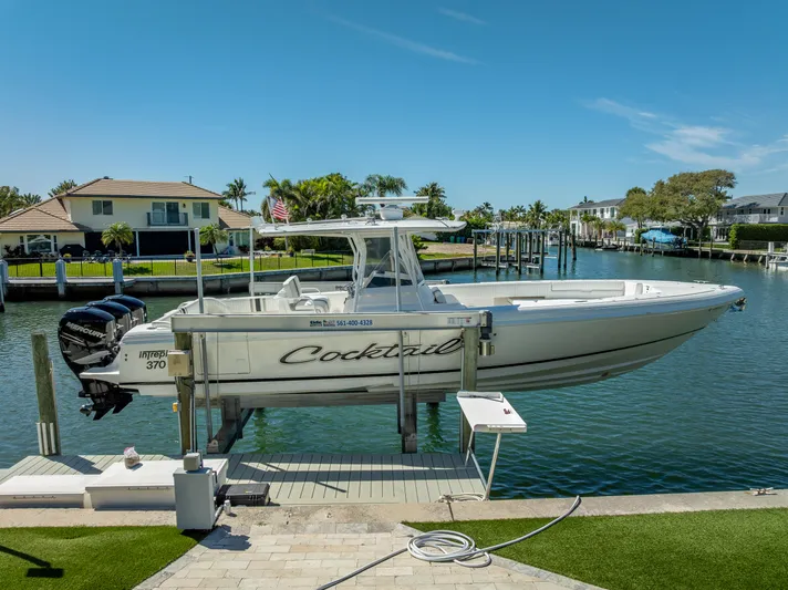  Yacht Photos Pics Intrepid 370 Open 2010 boat on lift by waterfront homes, clear sky.