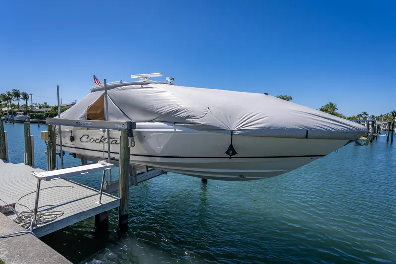  Yacht Photos Pics 2010 Intrepid 370 Open boat covered and docked on a lift by the water.