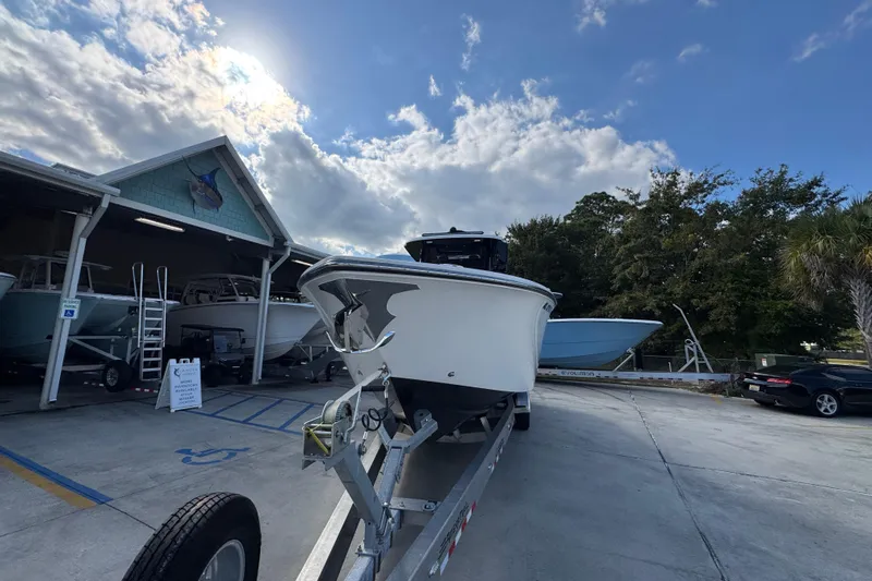 Yacht Photos Pics 2025 Fountain 32 NX boat on trailer under cloudy sky near storage facility.