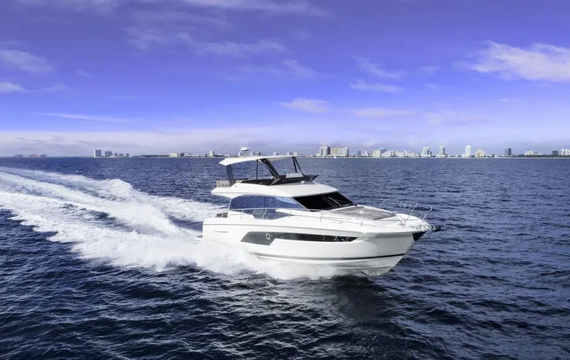 Soiral X Yacht Photos Pics 2023 Prestige 520 yacht cruising on open sea with city skyline in background.