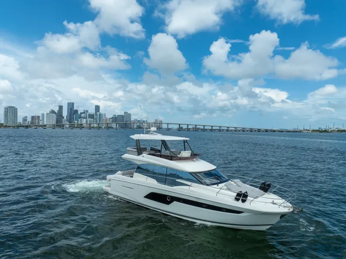 Soiral X Yacht Photos Pics 2023 Prestige 520 yacht cruising near a city skyline under a blue sky.