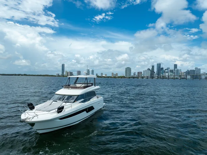 Soiral X Yacht Photos Pics Luxury 2023 Prestige 520 yacht cruising near city skyline under blue sky.