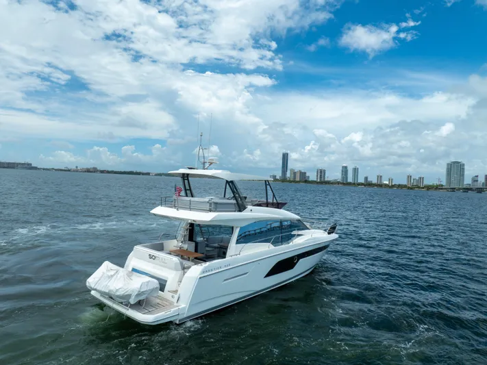 Soiral X Yacht Photos Pics 2023 Prestige 520 yacht cruising near city skyline under blue sky.