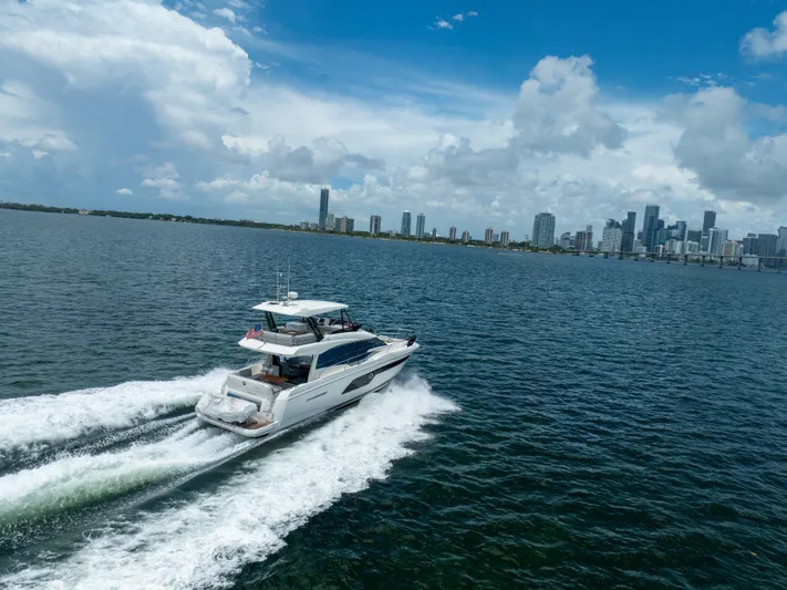 Soiral Yacht Photos Pics 2023 Prestige 520 yacht cruising near a city skyline under a blue sky.