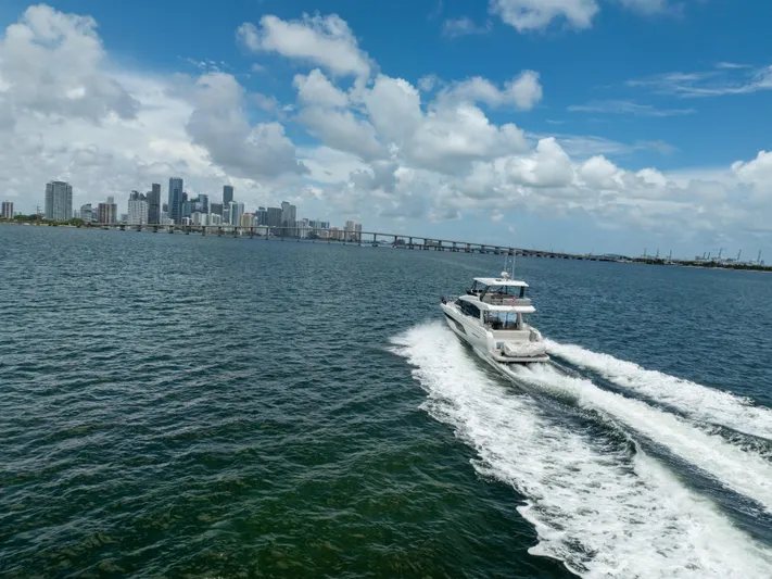 Soiral Yacht Photos Pics Luxury yacht Prestige 520 cruising near city skyline under blue sky, 2023 model.