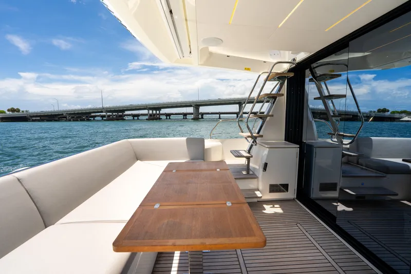 Soiral Yacht Photos Pics Luxurious 2023 Prestige 520 yacht deck with seating, table, and ocean view.