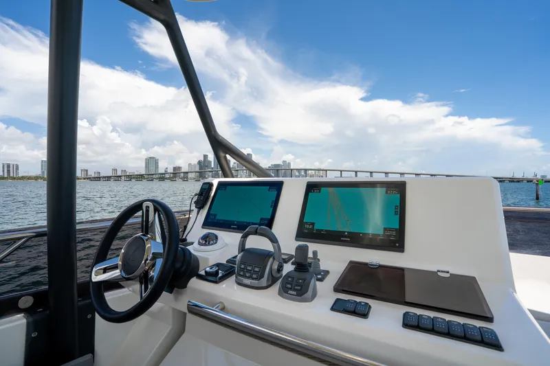 Soiral Yacht Photos Pics Helm of 2023 Prestige 520 yacht with navigation screens, overlooking city skyline and ocean.