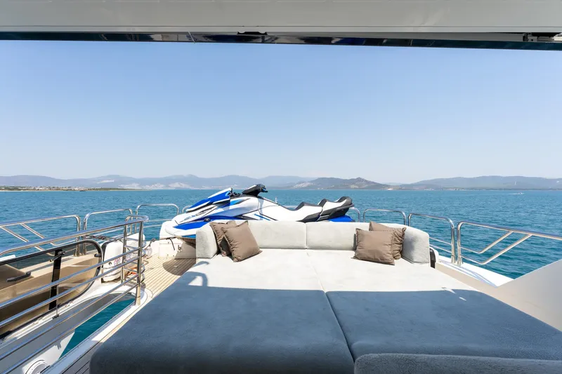 Mello Yacht Photos Pics Luxurious Sunseeker 86 Yacht deck with jet ski, overlooking serene ocean and distant mountains.
