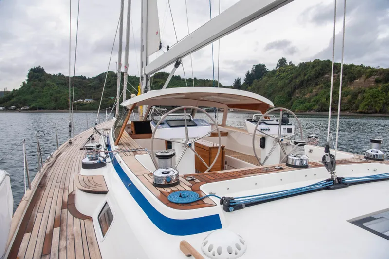 Hallberg Rassy 57 2020 Yacht Photos Pics 2020 Hallberg-Rassy 57 yacht with sleek deck design, anchored near lush shoreline.