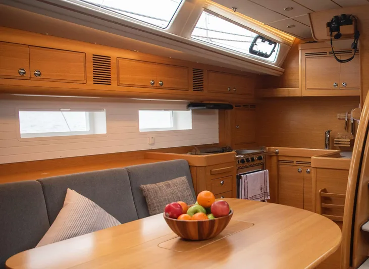 Hallberg Rassy 57 2020 Yacht Photos Pics Luxurious interior of 2020 Hallberg-Rassy 57 yacht with wooden cabinetry and dining area.