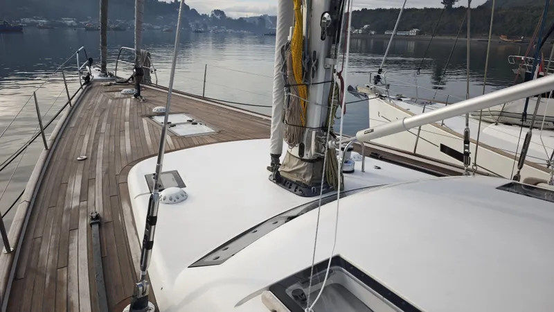 Hallberg Rassy 57 2020 Yacht Photos Pics 2020 Hallberg-Rassy 57 yacht deck with wooden finish, docked in a serene harbor.