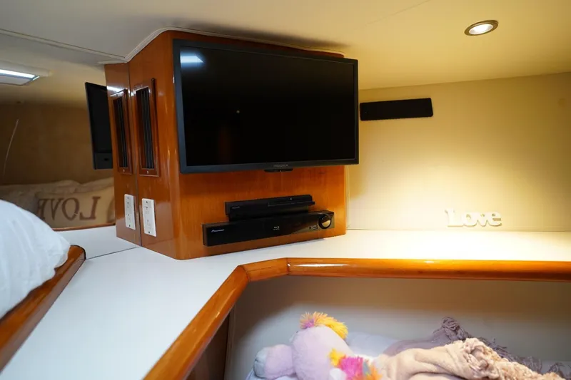 A2z's Yacht Photos Pics 1999 Viking 55 Convertible yacht interior with TV, wooden cabinetry, and cozy bedding.