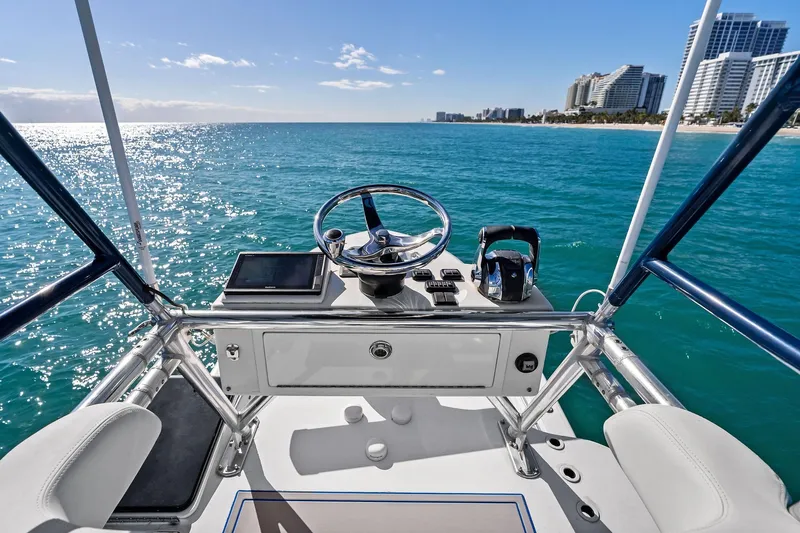  Yacht Photos Pics Helm of 2013 Invincible 42 Open Fisherman on clear blue ocean near city skyline.