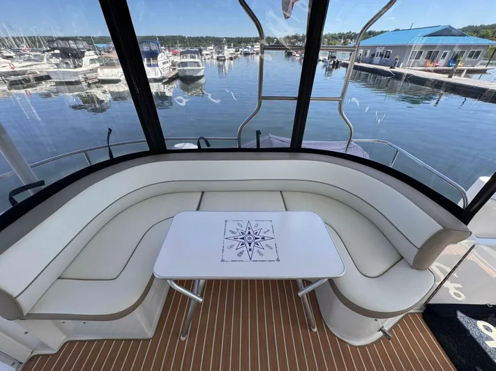  Yacht Photos Pics 2002 Cruisers Yachts 4450 Express Motor Yacht interior with curved seating and table, docked at marina.