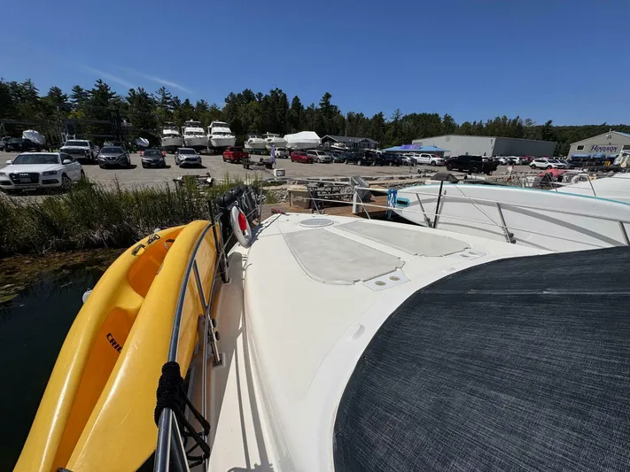  Yacht Photos Pics 2002 Cruisers Yachts 4450 Express Motor Yacht docked with yellow kayak on deck.