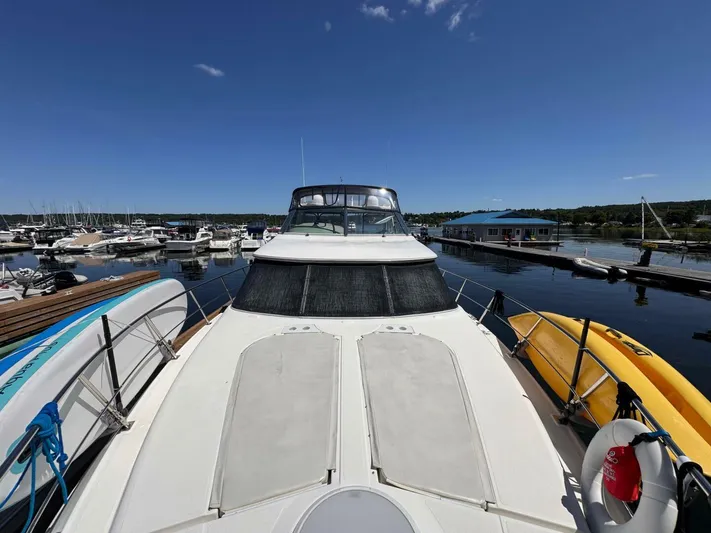  Yacht Photos Pics 2002 Cruisers Yachts 4450 Express Motor Yacht docked at marina under clear blue sky.