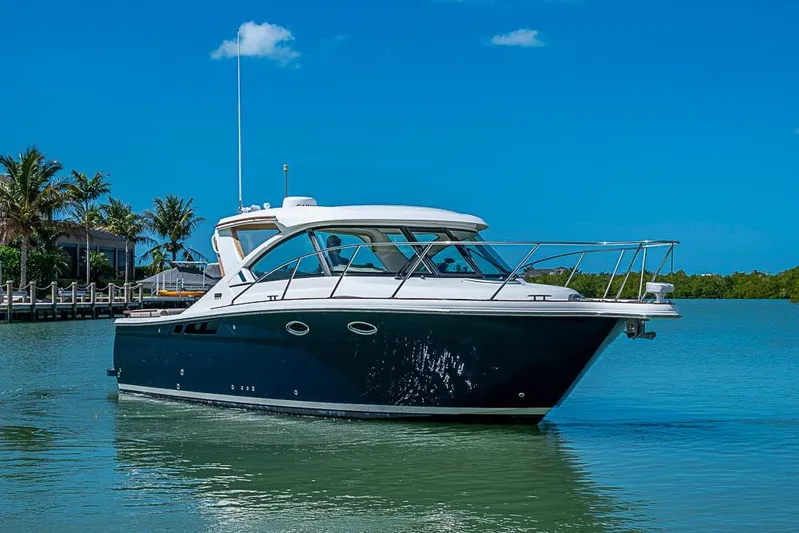 Float Me Alone Too Yacht Photos Pics 2012 Tiara Yachts 3100 Coronet cruising on a sunny day, surrounded by palm trees.