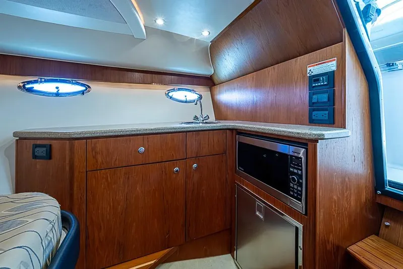 Float Me Alone Too Yacht Photos Pics 2012 Tiara Yachts 3100 Coronet interior with kitchenette, featuring wood cabinetry and modern appliances.