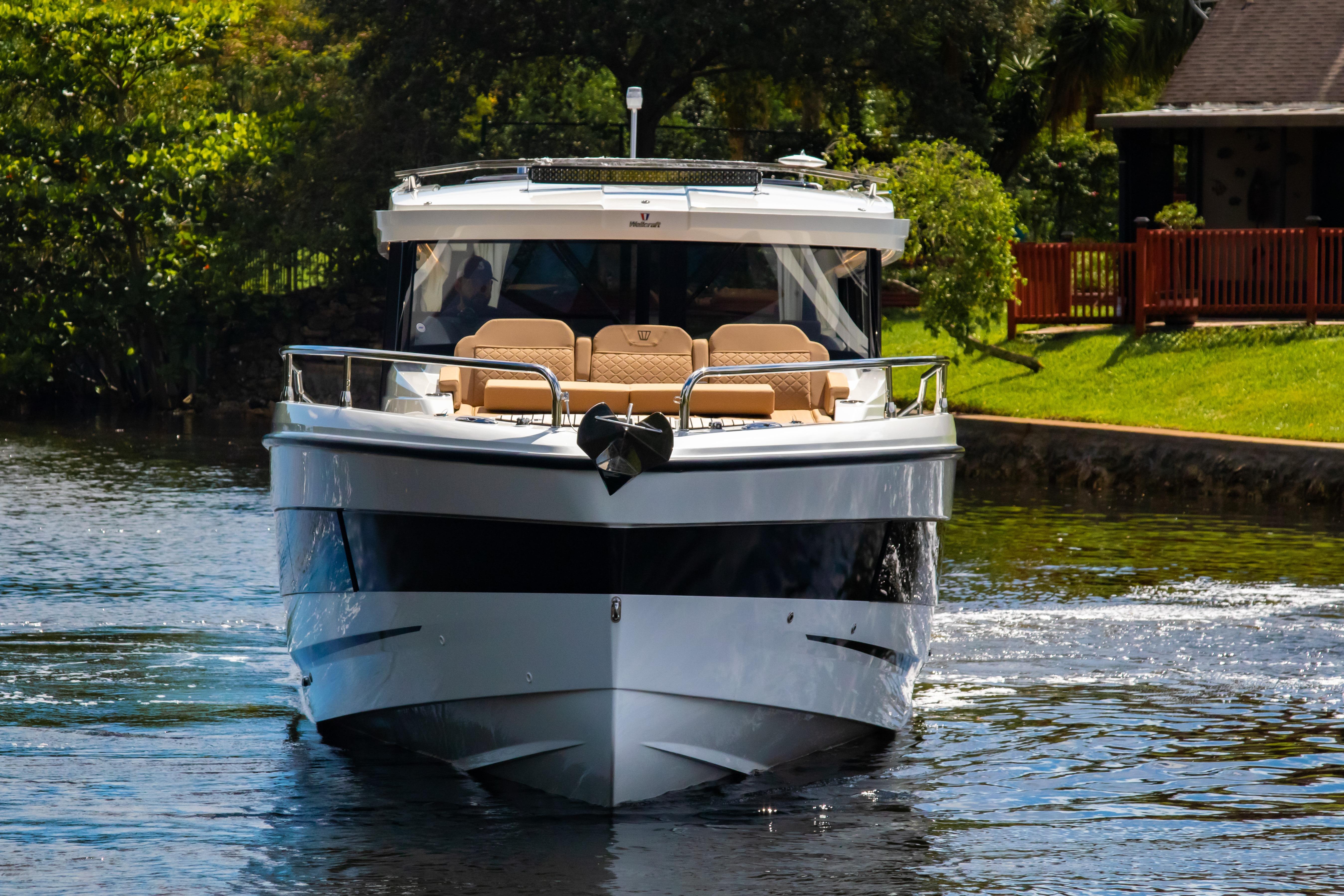 2025 Wellcraft 38 Explorer boat cruising on a serene river near lush greenery.
